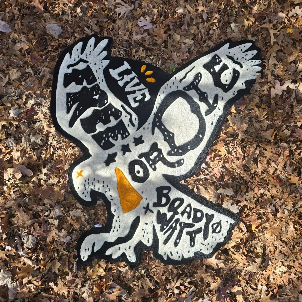 White eagle rug with the words Live Free Or Die, lying on autumn leaves